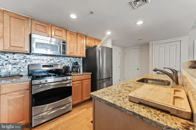 a kitchen with stainless steel appliances granite countertop a sink stove and refrigerator