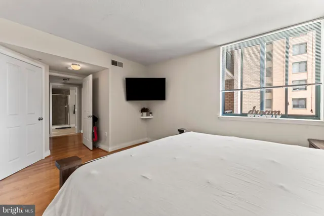 a bedroom with a bed and a flat tv screen on wall