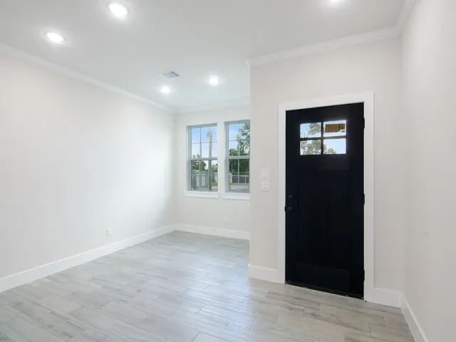 an empty room with wooden floor and windows