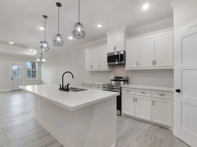 a kitchen with kitchen island granite countertop a sink stainless steel appliances and white cabinets