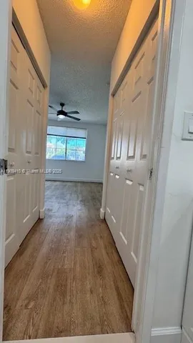 a view of empty room with wooden floor and fan
