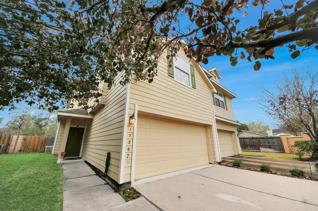 a view of a white house with a small yard and a large tree