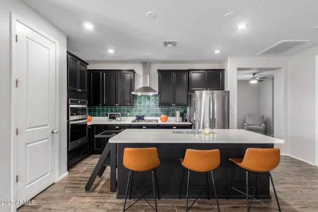 a kitchen with stainless steel appliances granite countertop a chairs a sink and a refrigerator