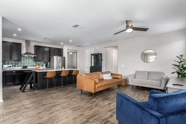 a living room with furniture kitchen view and a wooden floor