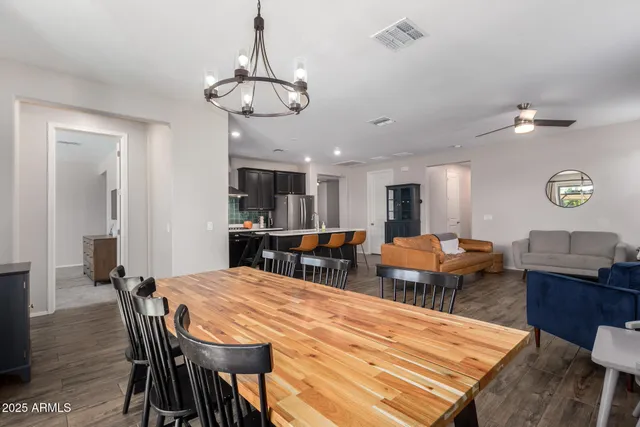 a dining room with wooden floor a chandelier a wooden table and chairs
