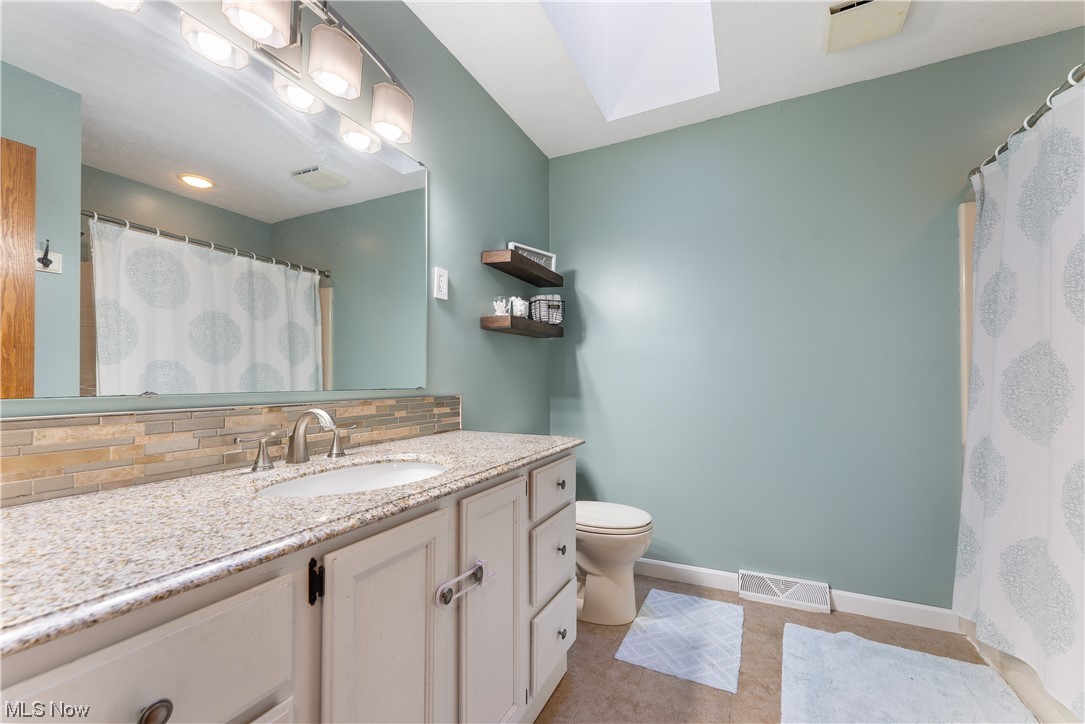 5226 Johnnycake Ridge Northeast Canton, OH 44705 - Photo 25 of 32 Bathroom with tile flooring, toilet, backsplash, a skylight, and vanity