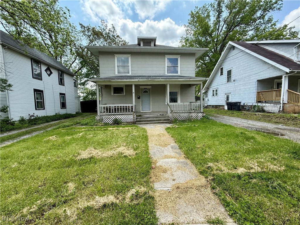 American foursquare style home with covered porch and a front lawn