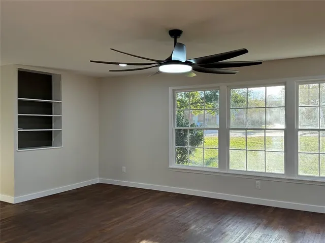 a view of an empty room with wooden floor and window