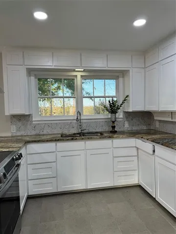 a kitchen with granite countertop a sink and white cabinets