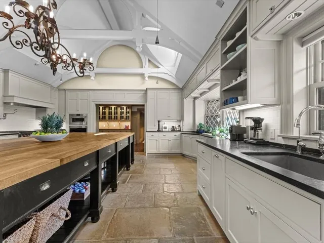 a large kitchen with a large counter space a sink and cabinets