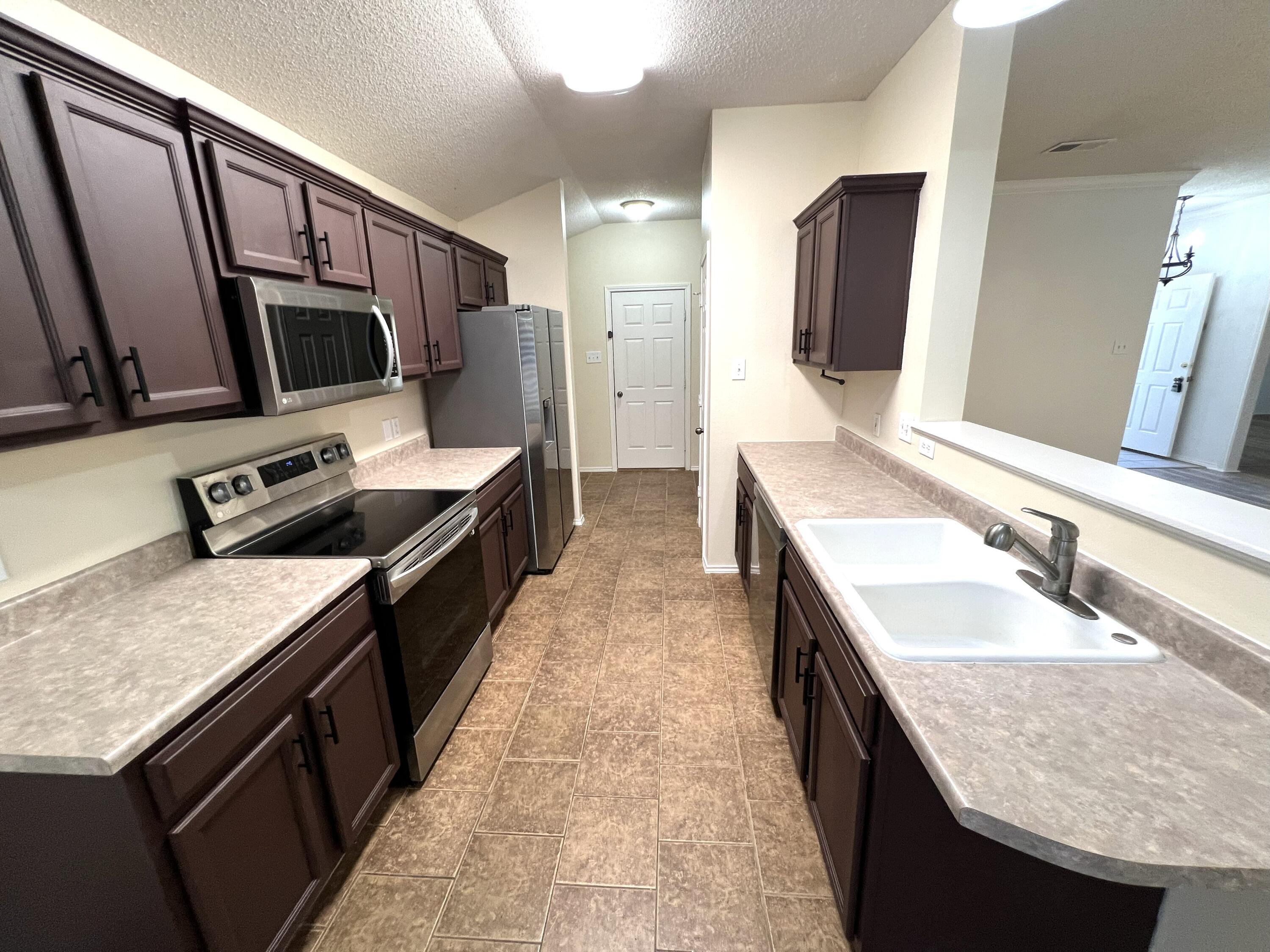 1707 76th Street Lubbock, TX 79423 - Photo 11 of 19 a kitchen with stainless steel appliances granite countertop a sink stove and refrigerator