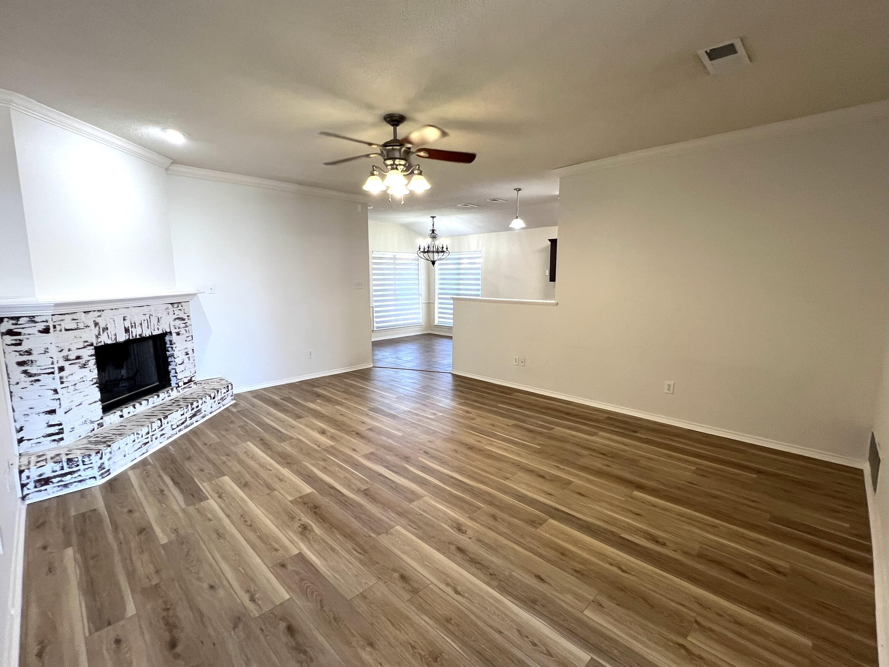 1707 76th Street Lubbock, TX 79423 - Photo 2 of 19 wooden floor in an empty room with a fireplace