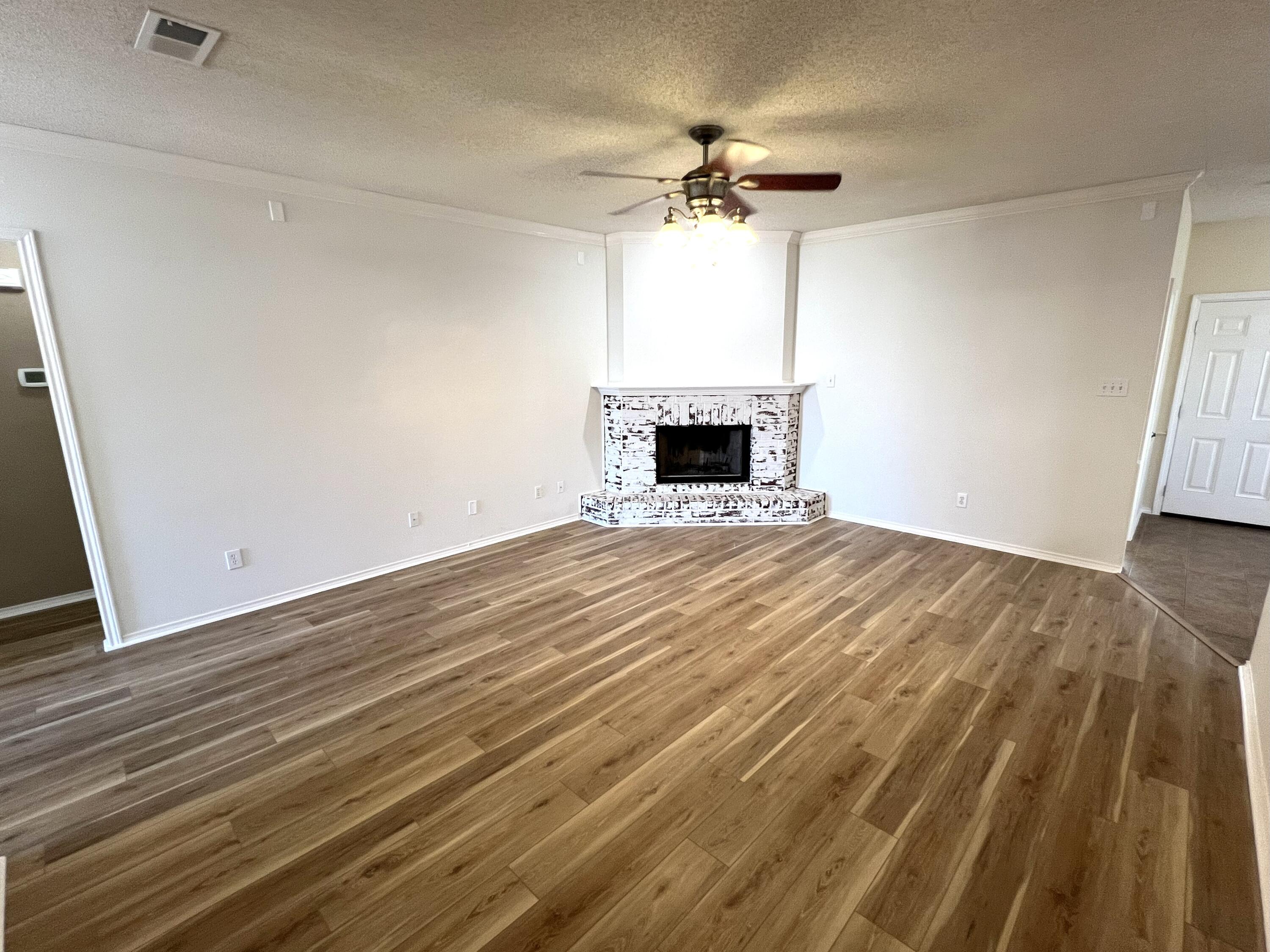1707 76th Street Lubbock, TX 79423 - Photo 3 of 19 a view of empty room with wooden floor and fireplace