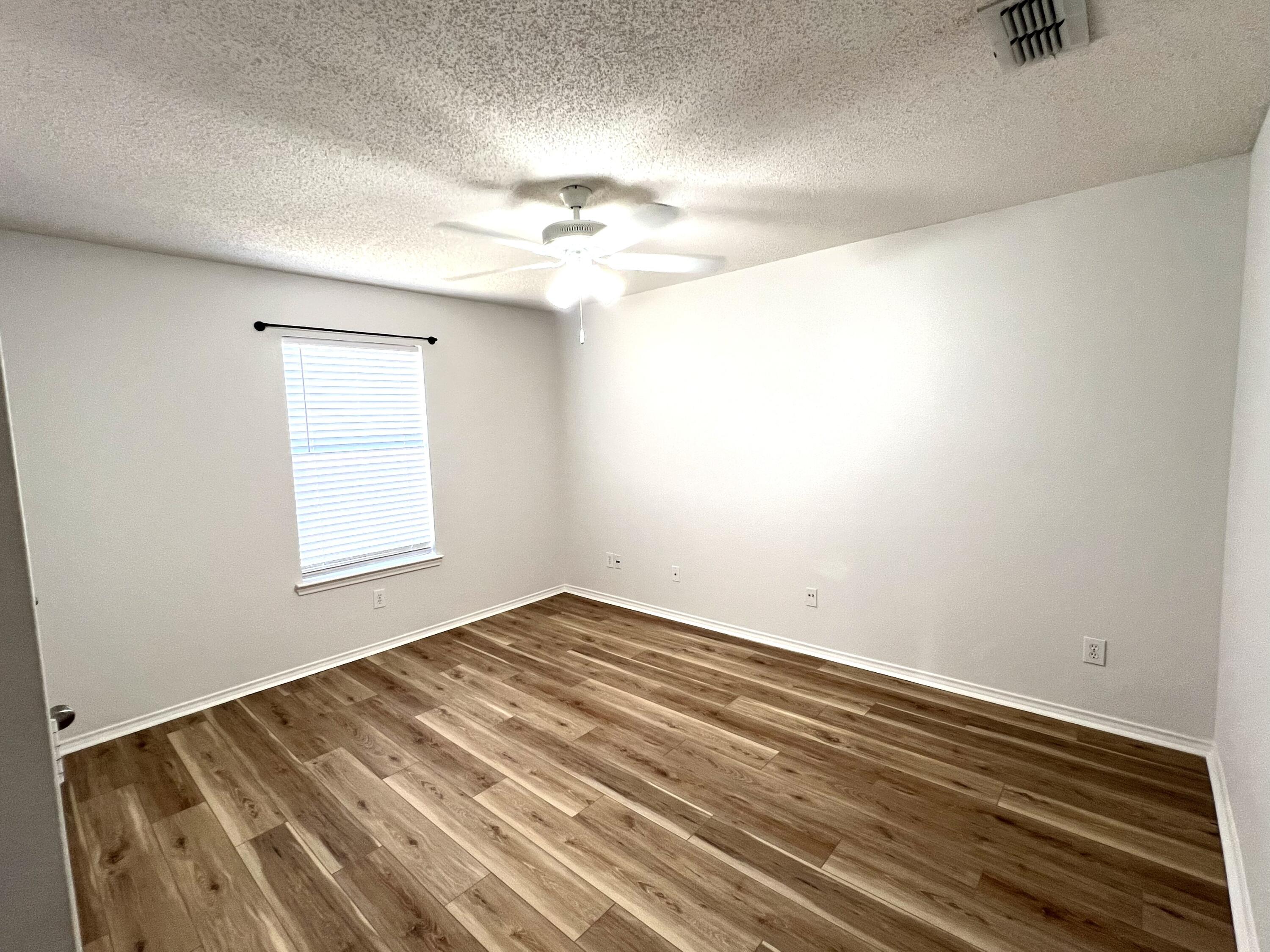 1707 76th Street Lubbock, TX 79423 - Photo 7 of 19 wooden floor in an empty room with a window