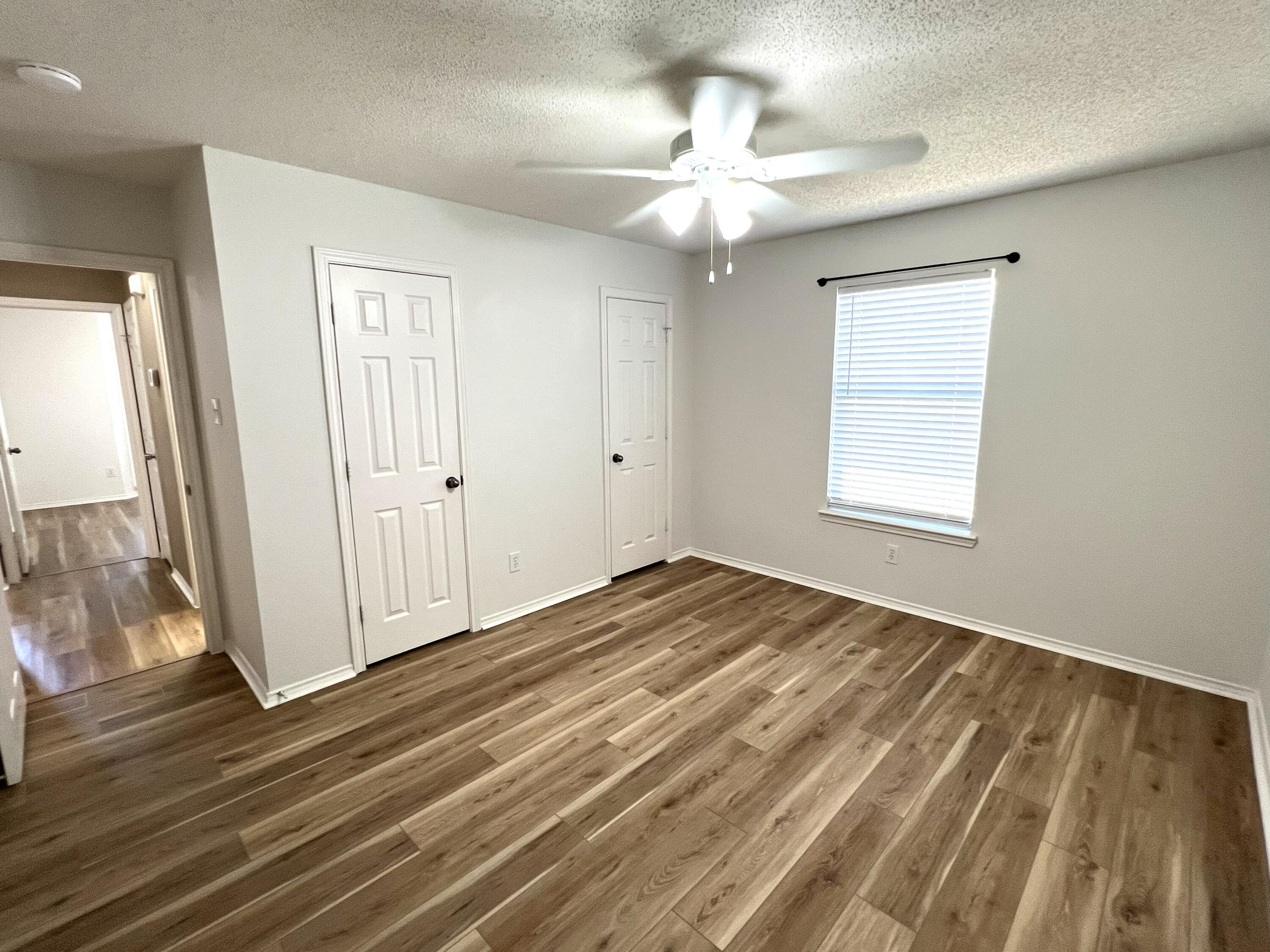 1707 76th Street Lubbock, TX 79423 - Photo 8 of 19 an empty room with wooden floor fan and windows