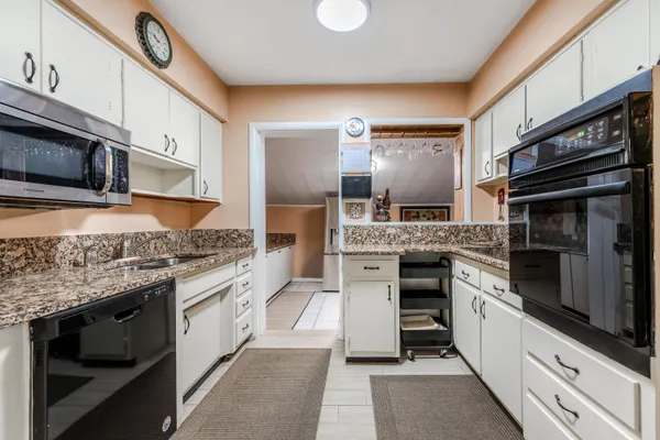 a kitchen with stainless steel appliances kitchen island granite countertop a stove top oven microwave and cabinets