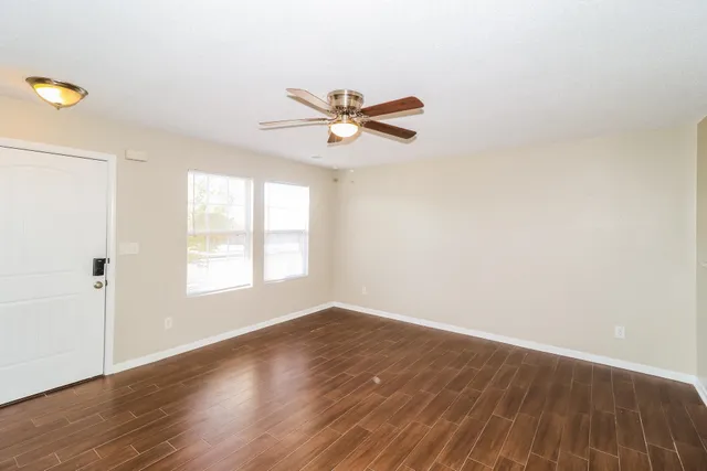 an empty room with wooden floor and windows