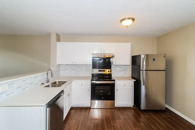 a kitchen with a sink a refrigerator and a stove top oven