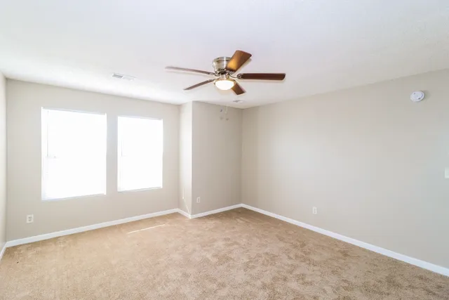 an empty room with windows and ceiling fan
