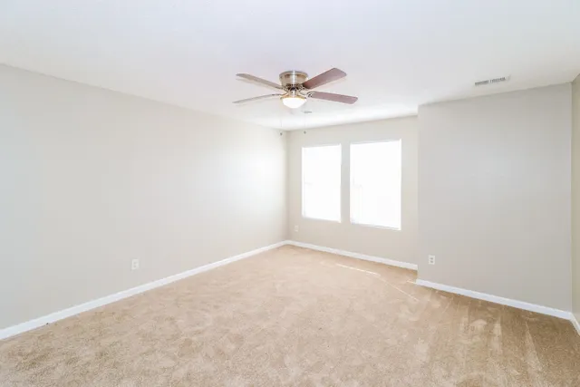 an empty room with windows and fan