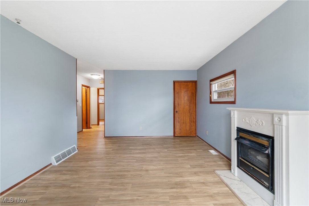 5415 12th Street Northwest Canton, OH 44708 - Photo 11 of 35 Unfurnished living room with visible vents, light wood-type flooring, baseboards, and a glass covered fireplace