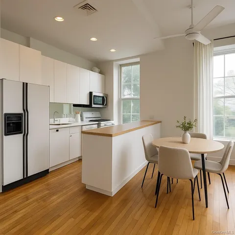 a kitchen with stainless steel appliances granite countertop a refrigerator a sink a stove a microwave and island with wooden floor