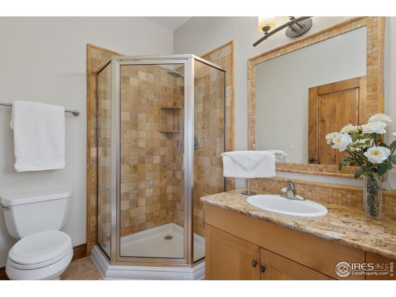 8467 Golden Eagle Road Fort Collins, CO 80528 - Photo 26 of 40 a bathroom with a granite countertop sink toilet a mirror and shower