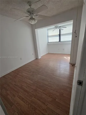a view of empty room with wooden floor and fan