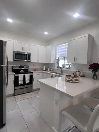 a kitchen with stainless steel appliances a sink a stove a microwave a refrigerator and cabinets