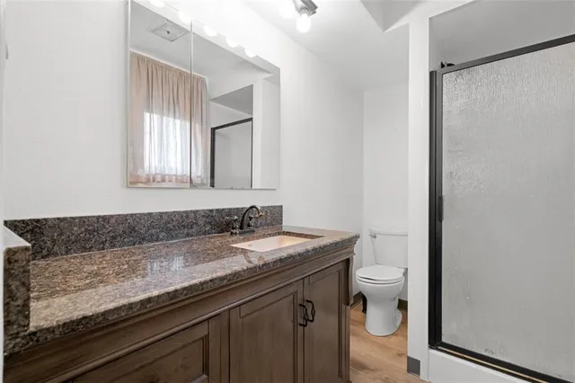 a bathroom with a granite countertop sink a toilet and a mirror