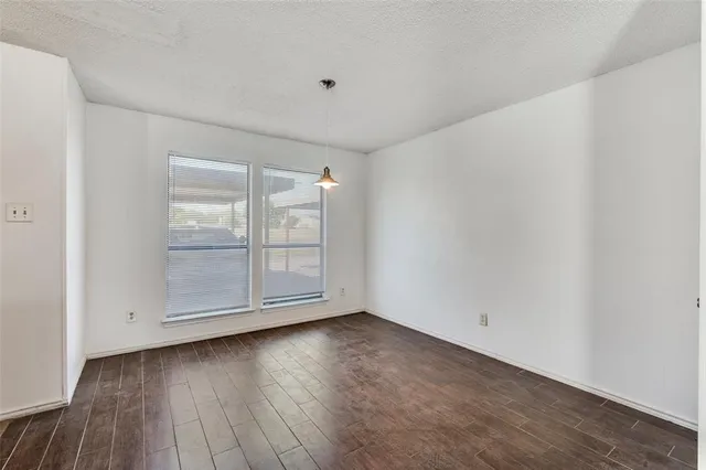 an empty room with a chandelier fan and windows