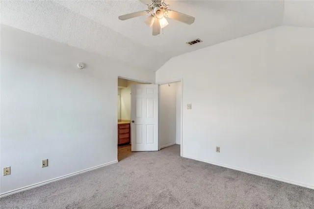 an empty room with a chandelier fan and windows