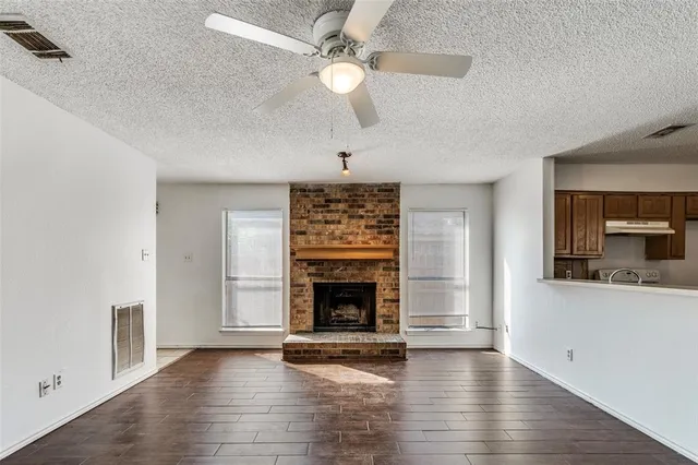 an empty room with fireplace wooden floor and windows