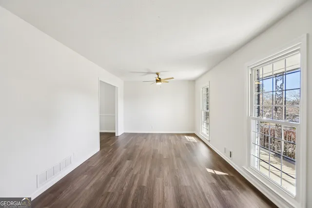 an empty room with wooden floor cabinet and windows