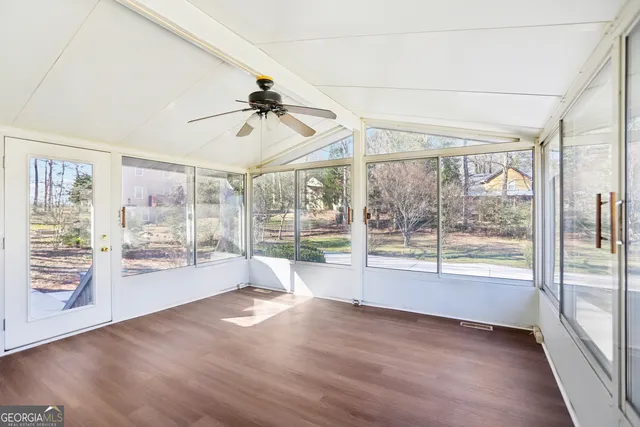a view of empty room with wooden floor and fan