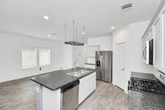 a kitchen that has a sink a center island stainless steel appliances and cabinets