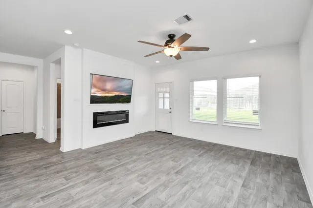 a view of an empty room with a window and wooden floor