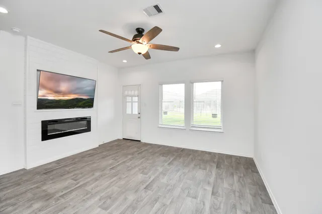 a view of empty room with wooden floor and fan