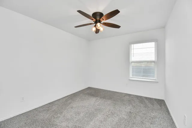 an empty room with window and ceiling fan