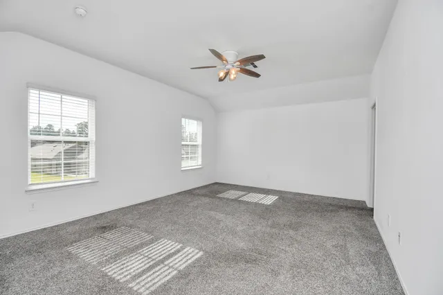 an empty room with windows and fan