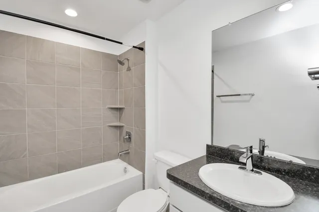 a bathroom with a granite countertop sink toilet a mirror and shower
