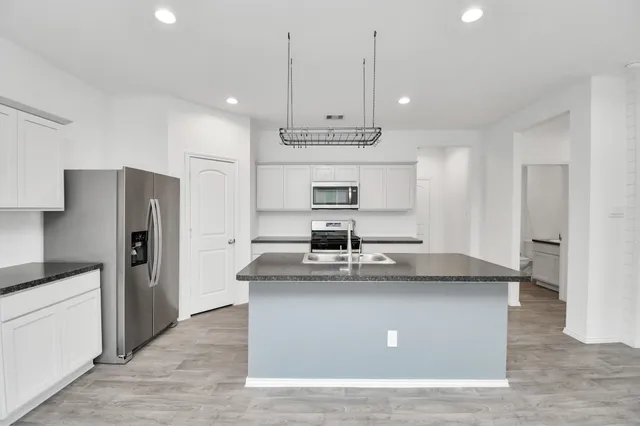 a kitchen with kitchen island a counter top space a sink stainless steel appliances and cabinets