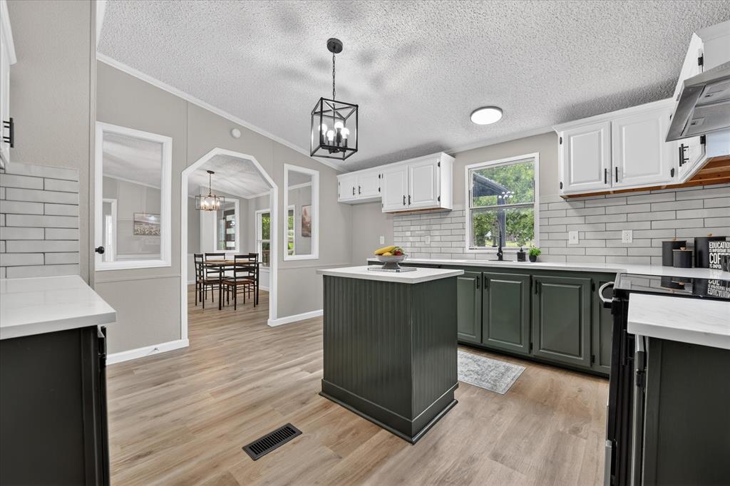 134 Classic Country Court Springtown, TX 76082 - Photo 11 of 35 Kitchen featuring wood-finish flooring, white countertops, subway tile backsplash, and a central island