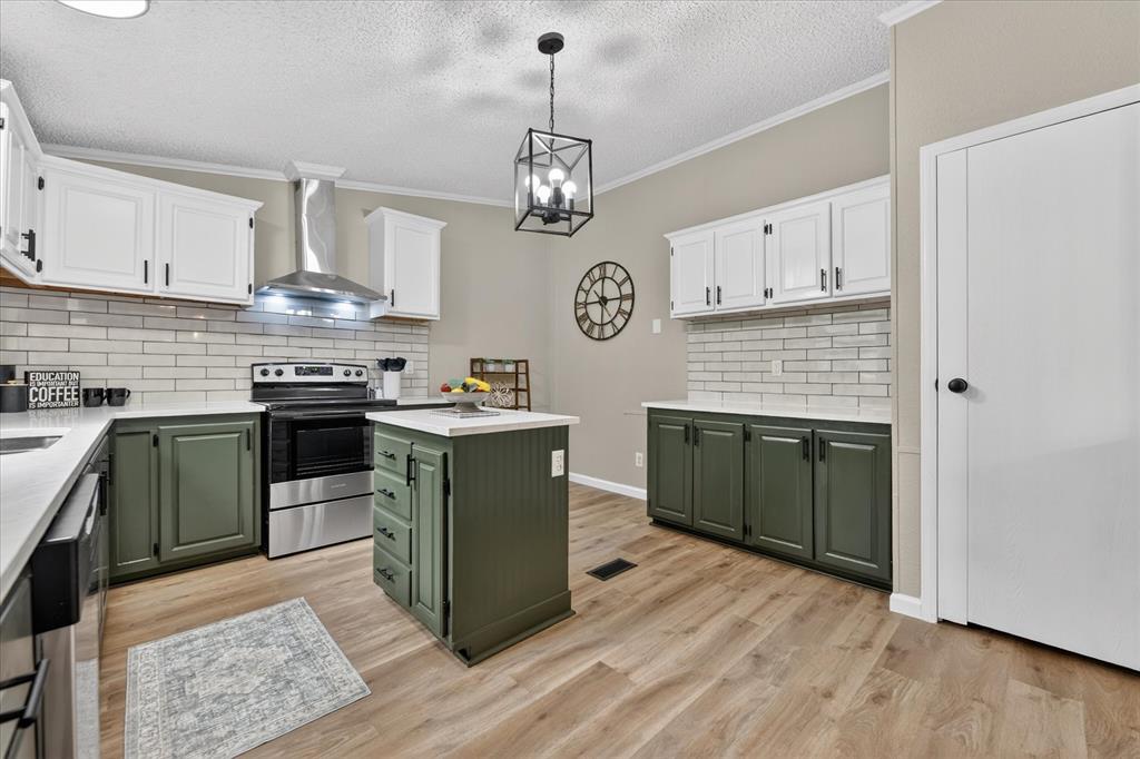 134 Classic Country Court Springtown, TX 76082 - Photo 13 of 35 Kitchen featuring a center island, wood-finish flooring, two-tone cabinetry with white uppers and green lowers, a stainless steel range with a matching range hood, and a subway tile backsplash