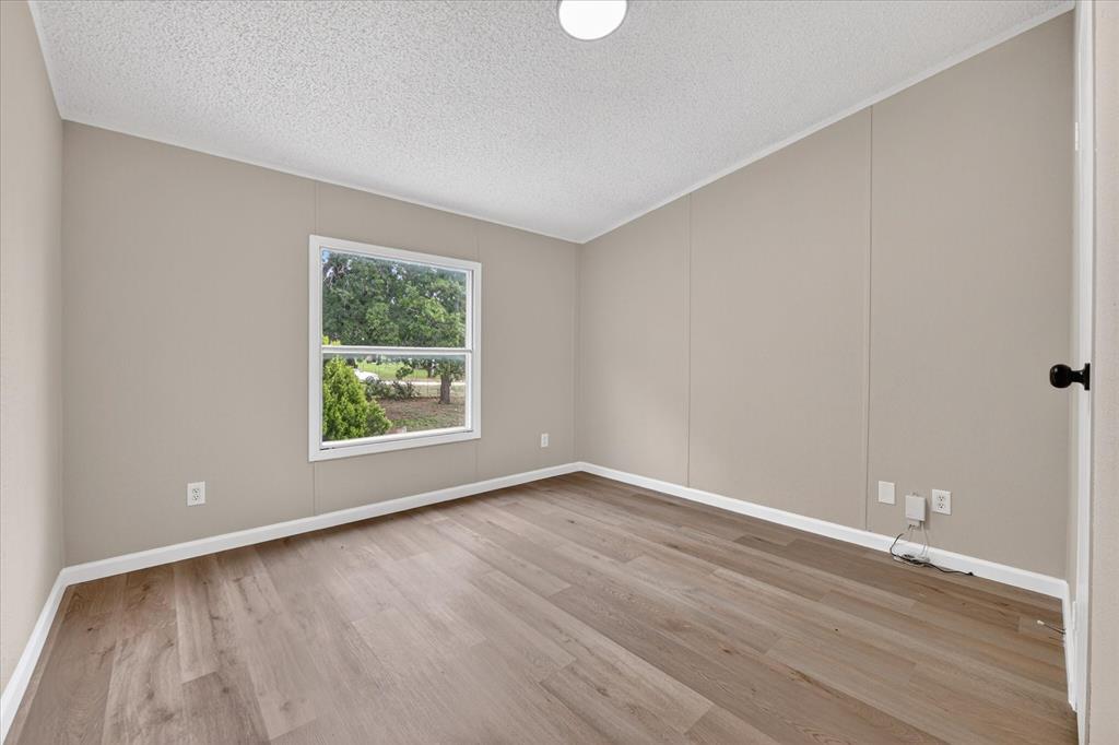 134 Classic Country Court Springtown, TX 76082 - Photo 14 of 35 Spacious room featuring wood-finish flooring, neutral-toned walls, a white trim package, and a double-hung window