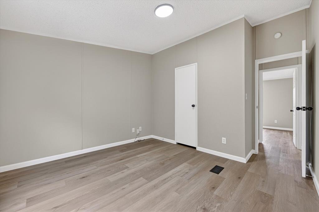 134 Classic Country Court Springtown, TX 76082 - Photo 15 of 35 Room featuring wood-finish flooring, light gray wall paneling, white baseboards, and a flush-mount ceiling light fixture