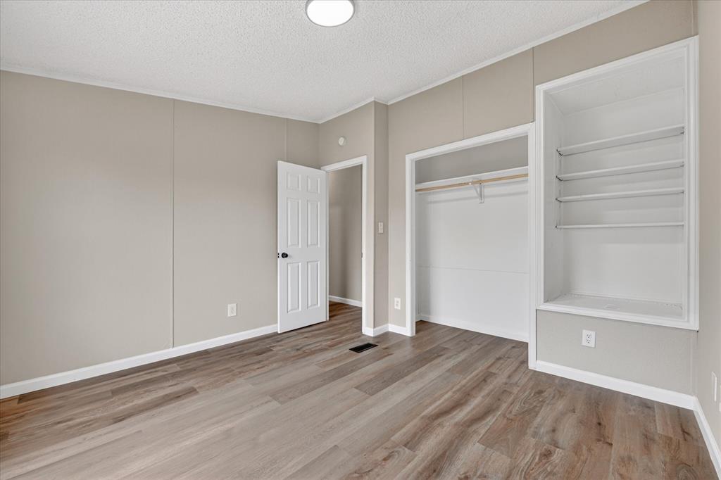134 Classic Country Court Springtown, TX 76082 - Photo 18 of 35 Interior space featuring wood-finish flooring, light grey walls, white trim, a built-in closet, and built-in shelving