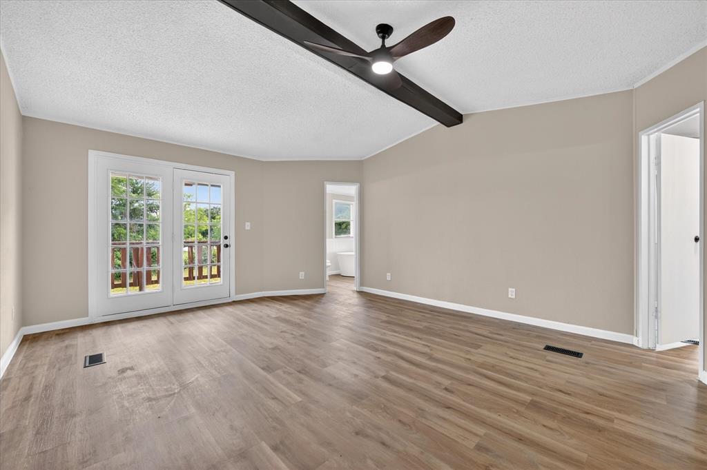 134 Classic Country Court Springtown, TX 76082 - Photo 21 of 35 Spacious room featuring wood-finish flooring, neutral-toned walls, and a white textured ceiling