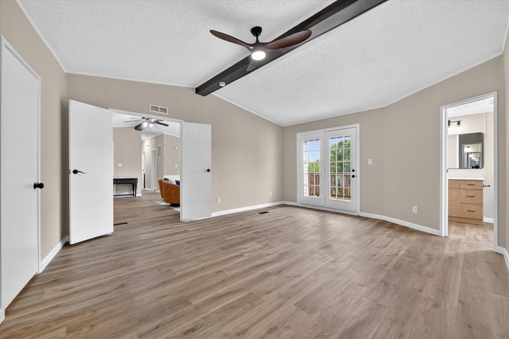 134 Classic Country Court Springtown, TX 76082 - Photo 22 of 35 Spacious room featuring wood-finish flooring, neutral-toned walls, and a vaulted ceiling with exposed beam and ceiling fan