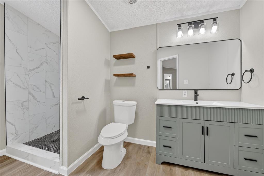 134 Classic Country Court Springtown, TX 76082 - Photo 24 of 35 Contemporary bathroom featuring a spacious walk-in shower with large format tile, a modern vanity with integrated sink, rectangular mirror, and matte black fixtures